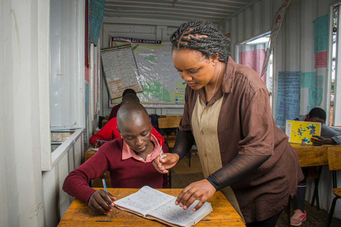 Teacher helping a student at a desk in a classroom